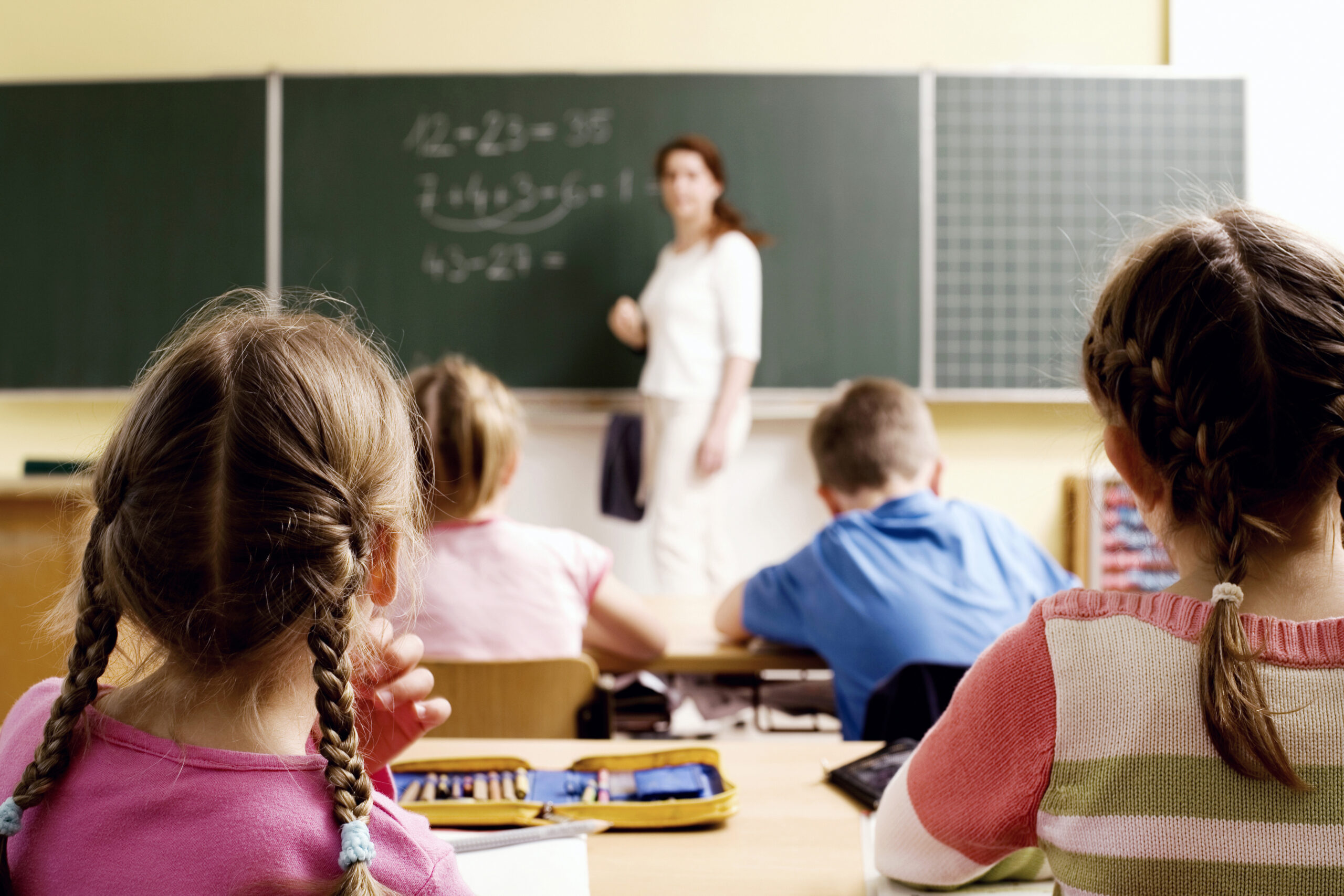 Teacher writing on a board in front of several children and children being comfrtable is important when choosing the right learning environment for your child