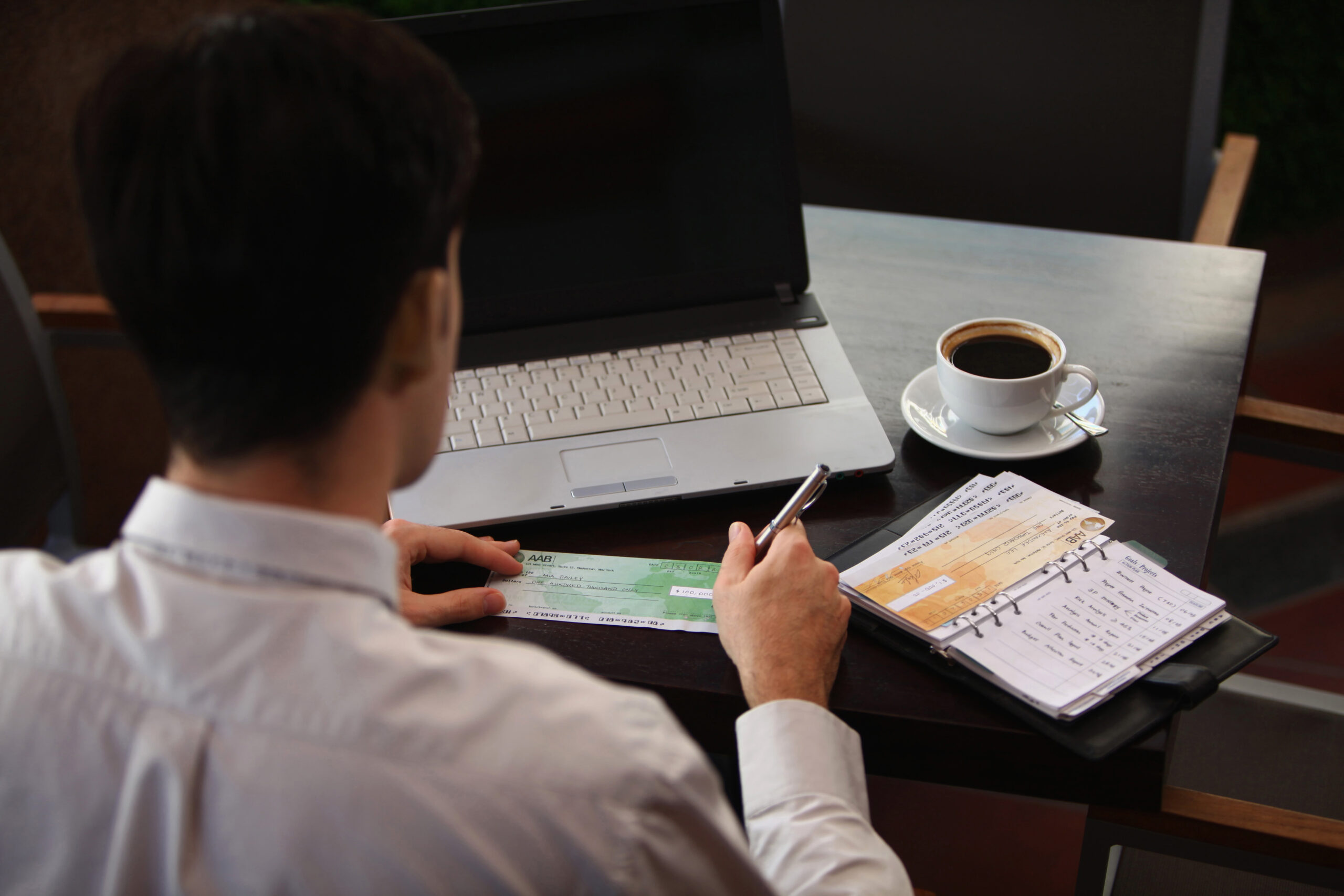 Man sat at a laptop with a coffee and notebook as what you need to know before investing