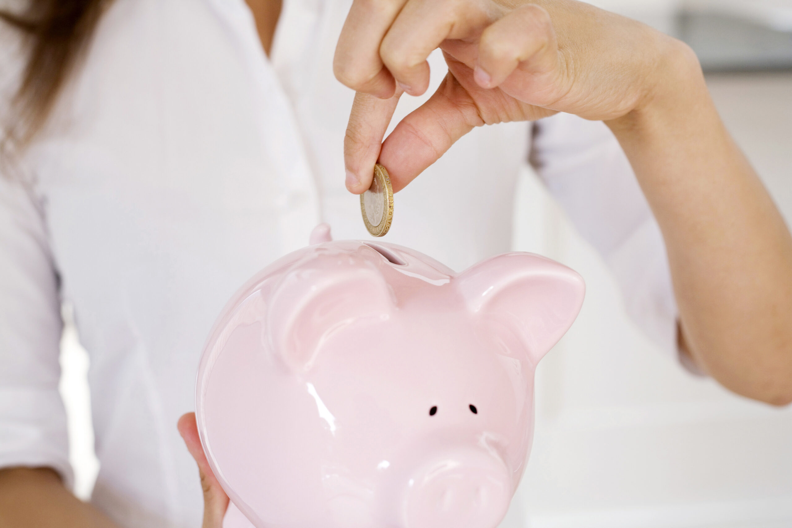 Woman putting money into a piggy bank whilst thinking about different types of loans