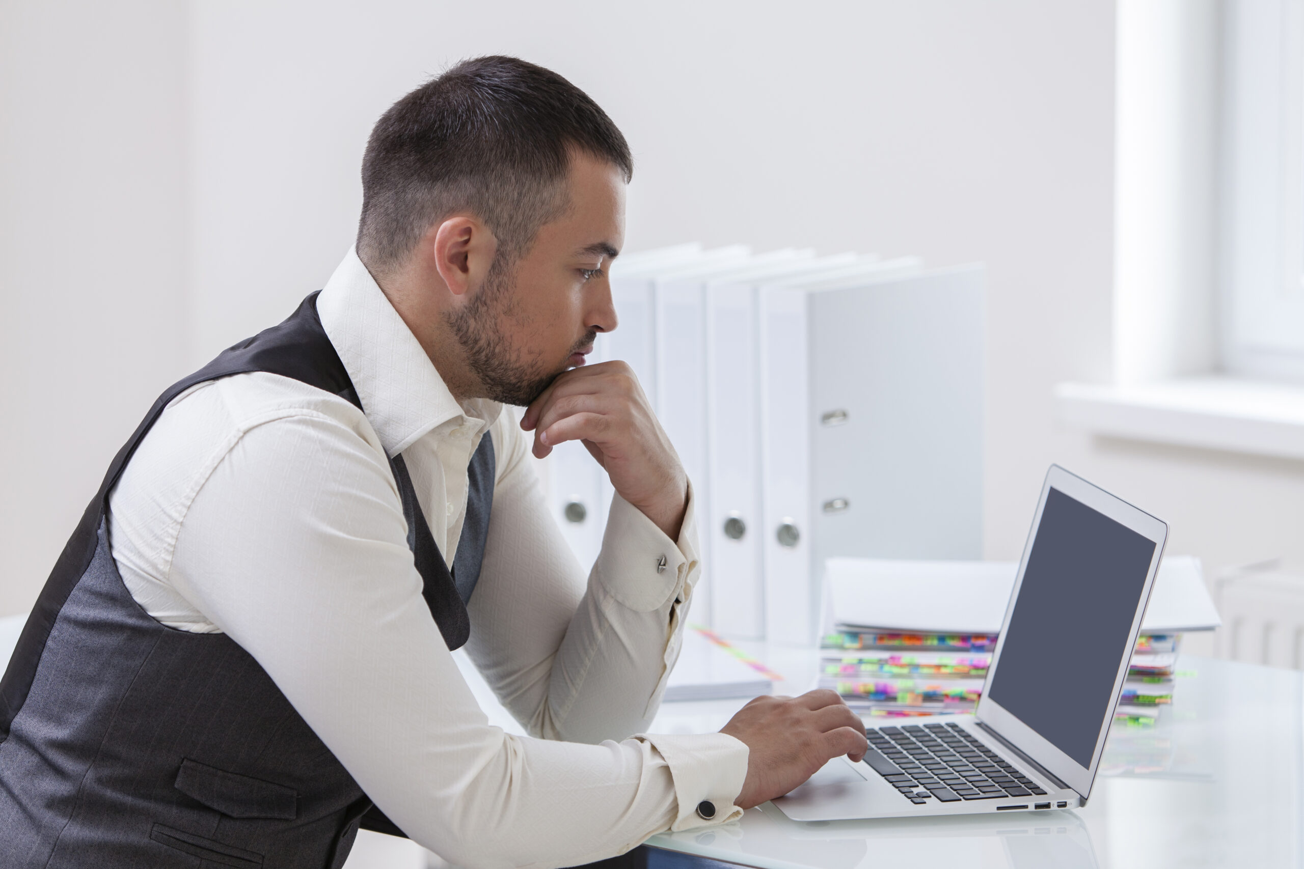 Young businessman using at laptop at desk as thinking about ways to build your brand