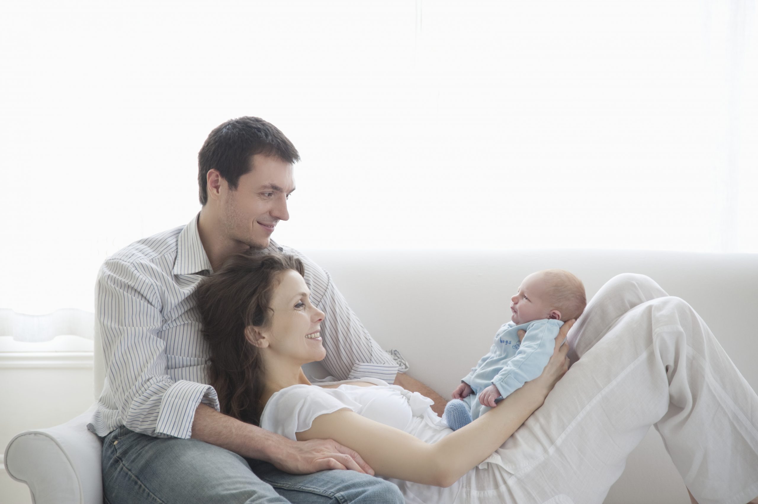 A woman holder her newborn baby with partner behind her how to keep your mind sharp as a new parent