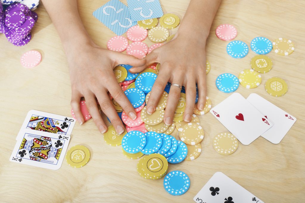 Female hands holding gambling chips with cards around the table
