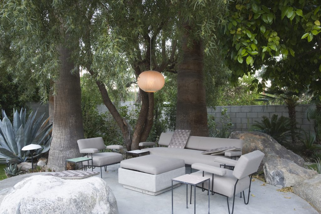 Stone garden with rocks and trees surrounding and stone coloured furniture adorning