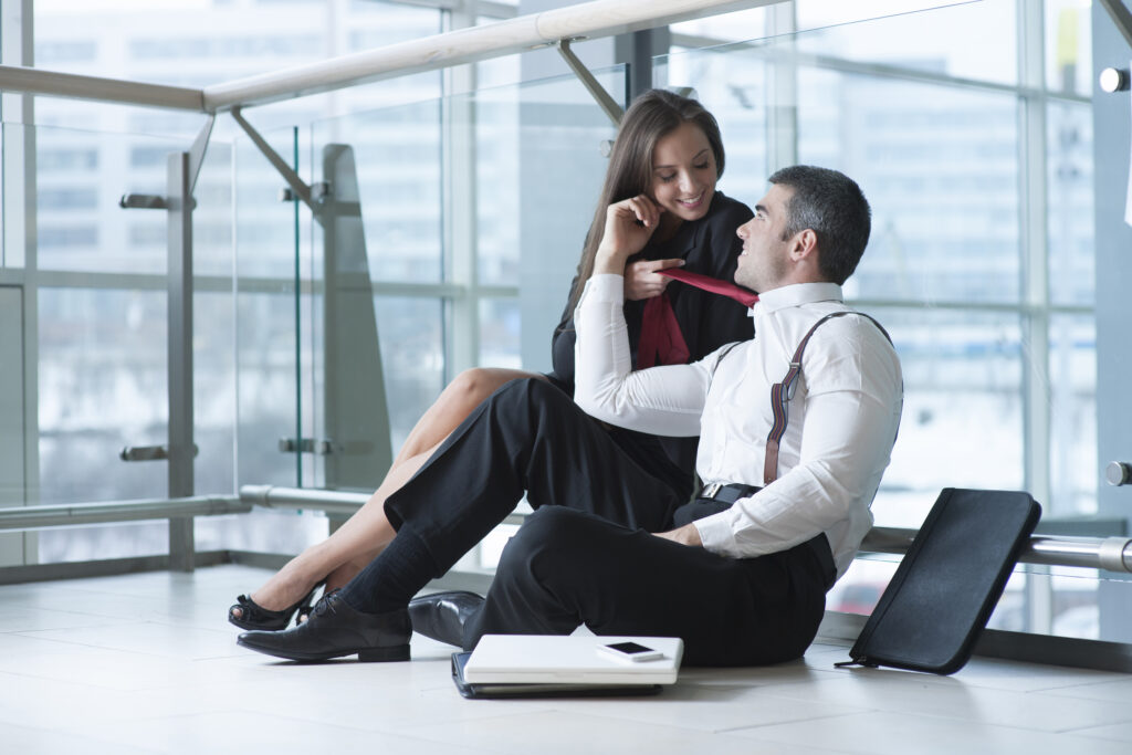 Businesswoman pulls male coworker towards her with his tie whilst role playing