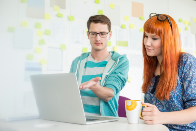 Successful Merch Selling Tips for YouTubers Businessman showing something to female colleague on laptop in creative office